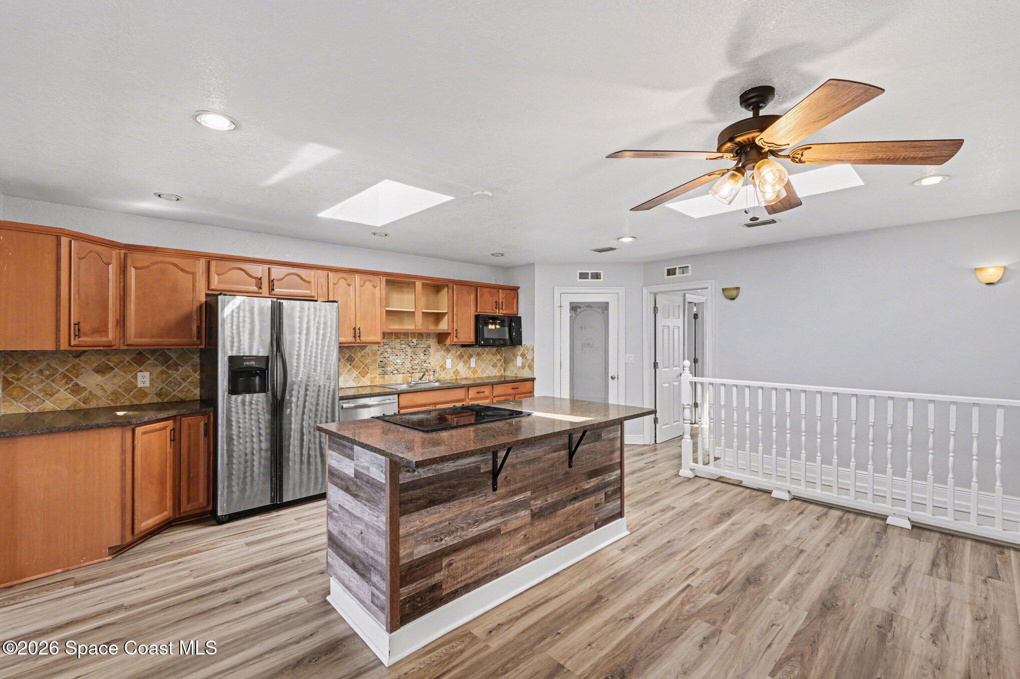4950 Blounts Ridge Road Mims, FL 32754 - Photo 21 of 40 a kitchen with stainless steel appliances granite countertop a refrigerator a sink dishwasher a stove and white countertops with wooden floor