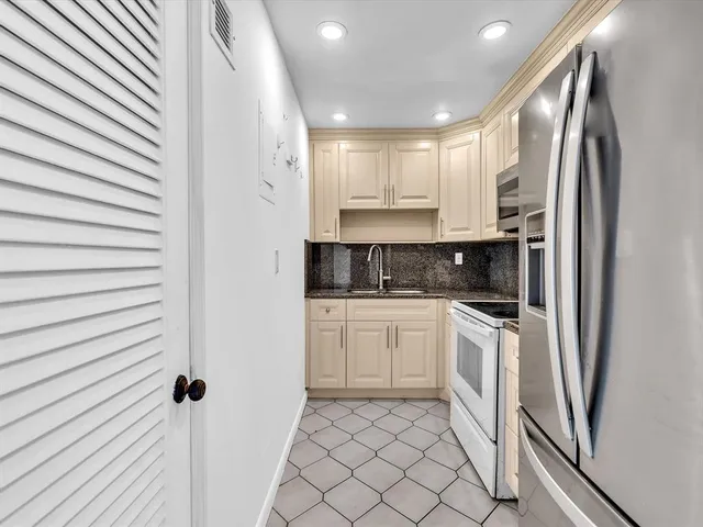 a kitchen with stainless steel appliances granite countertop a refrigerator sink and white cabinets