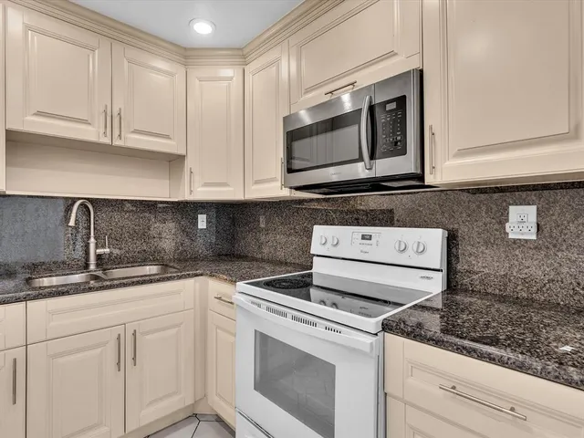 a kitchen with granite countertop white cabinets and white appliances