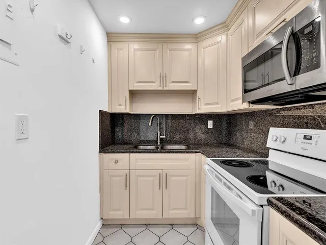 a kitchen with granite countertop white cabinets and stainless steel appliances