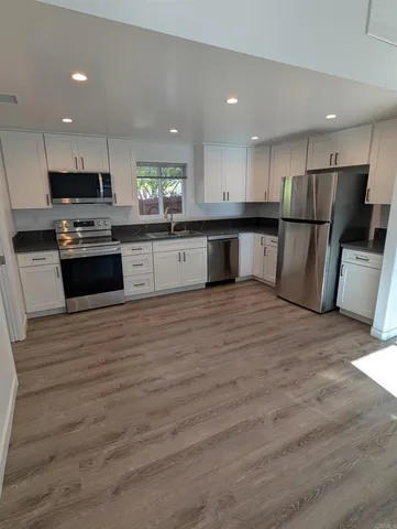 a large kitchen with stainless steel appliances granite countertop a large counter top a stove a microwave and a refrigerator