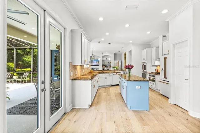 a living room with stainless steel appliances furniture wooden floor and a large window