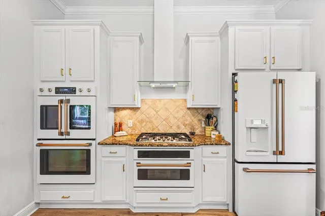 a kitchen with stainless steel appliances granite countertop white cabinets and a stove