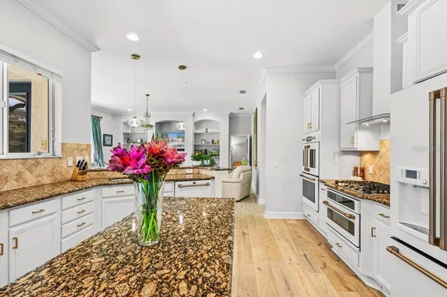 a kitchen with granite countertop white cabinets sink and stainless steel appliances