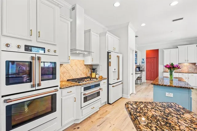 a kitchen with stainless steel appliances granite countertop a refrigerator stove and white cabinets