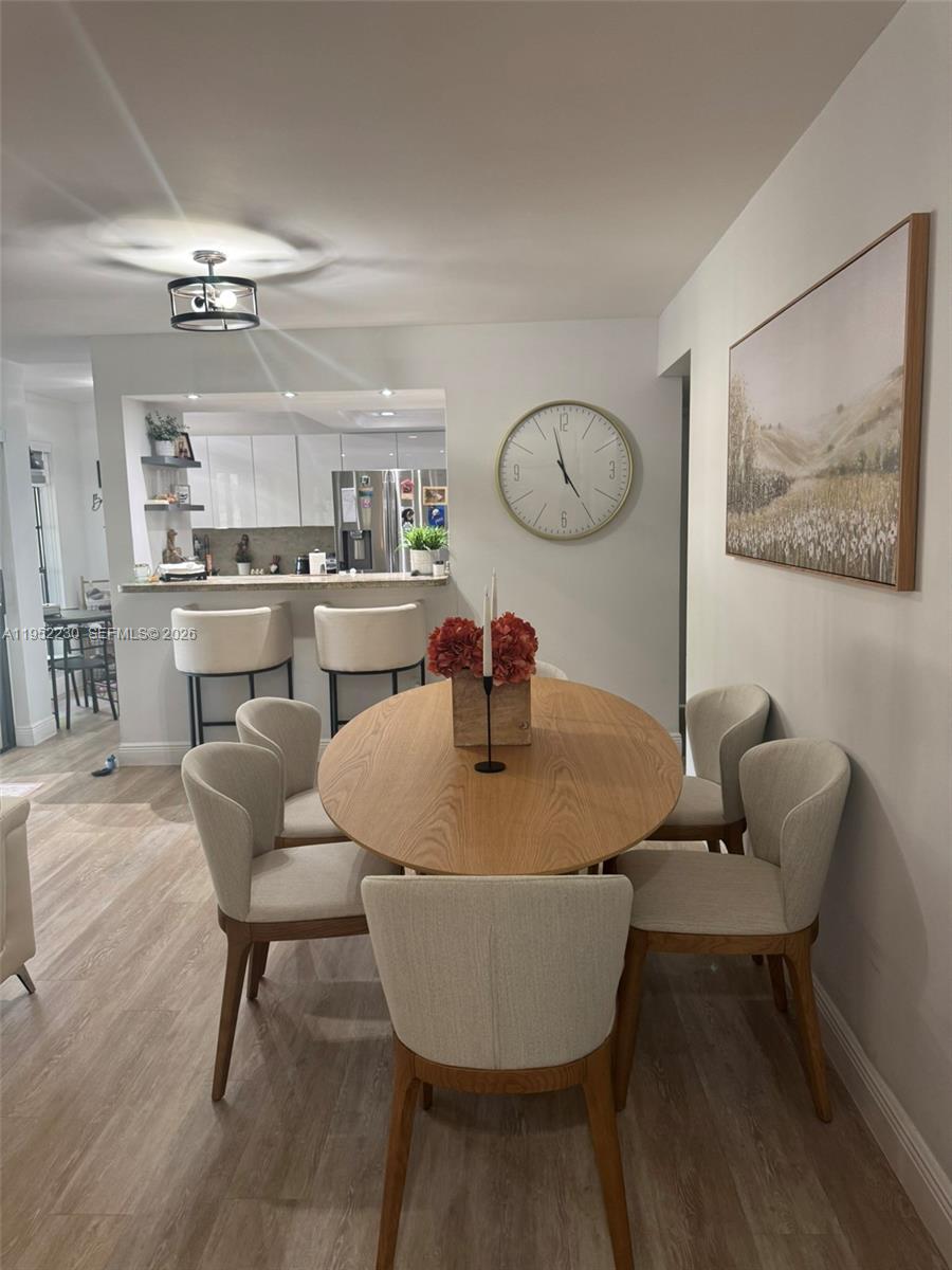 8810 Southwest 123rd Court, Unit M202 Miami, FL 33186 - Photo 6 of 34 a dining room with wooden floor a chandelier a wooden table and chairs