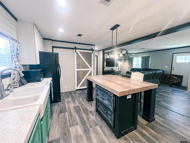 a kitchen with a stove a refrigerator a sink dishwasher with a dining table and chairs with wooden floor