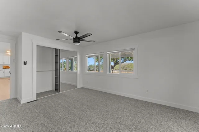 an empty room with window and ceiling fan