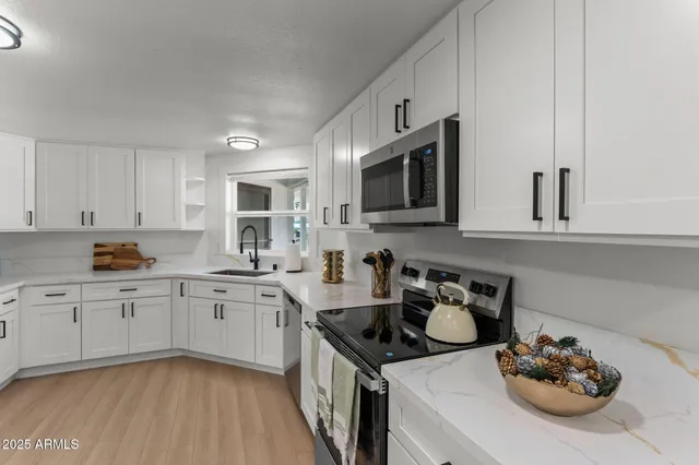 a kitchen with stainless steel appliances granite countertop a sink stove and microwave with wooden floor