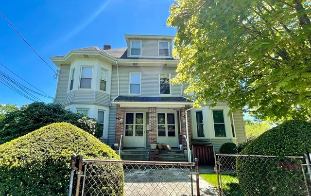 a view of a white house with large windows and a small yard