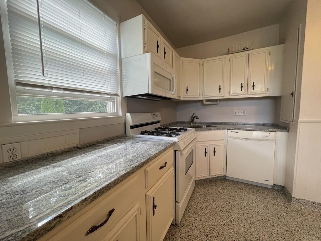 36-2 Lowell Avenue, Unit 362 Newton, MA 02460 - Photo 4 of 22 a kitchen with granite countertop white cabinets and white appliances