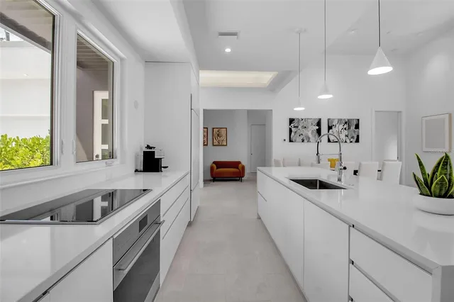 a large white kitchen with a sink and large window