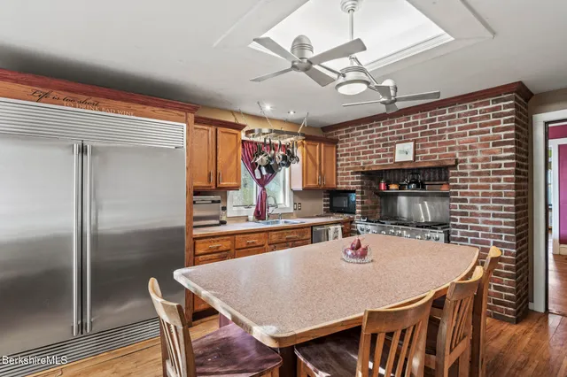 a kitchen with stainless steel appliances granite countertop a dining table chairs and white cabinets