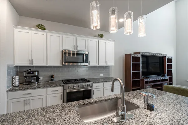 a kitchen with granite countertop a stove a sink and a microwave