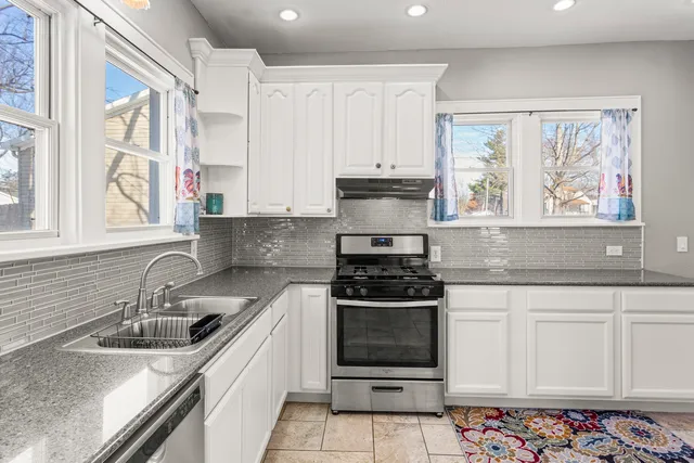 a kitchen with stainless steel appliances granite countertop a stove a sink and a white cabinets
