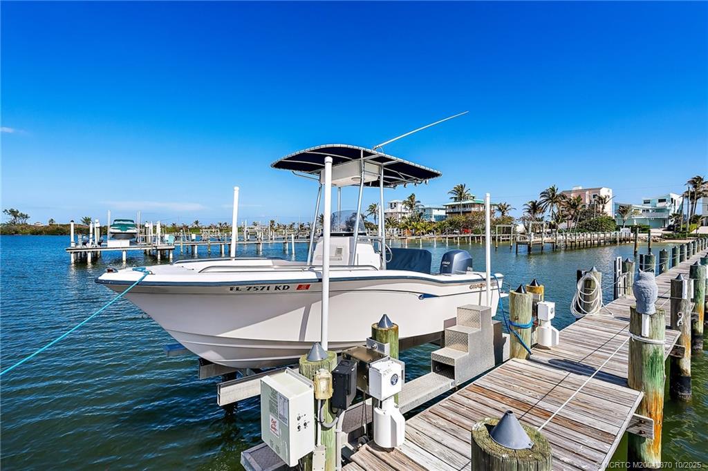 777 Southeast MacArthur Boulevard Stuart, FL 34996 - Photo 36 of 46 a roof deck with table and chairs a barbeque with wooden floor and city view
