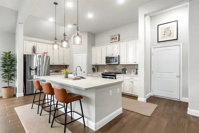 a kitchen with stainless steel appliances a white refrigerator stove a sink and white cabinets with wooden floor