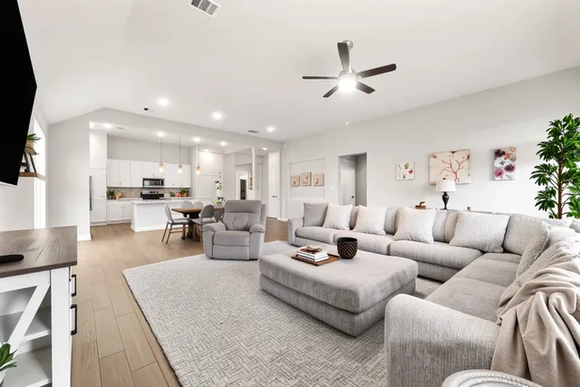 a living room with furniture kitchen view and a chandelier