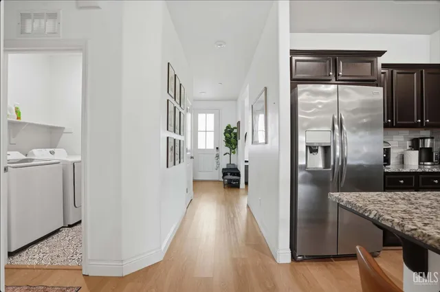 a kitchen with stainless steel appliances granite countertop a stove top oven a sink a refrigerator with a dining table and chairs with wooden floor