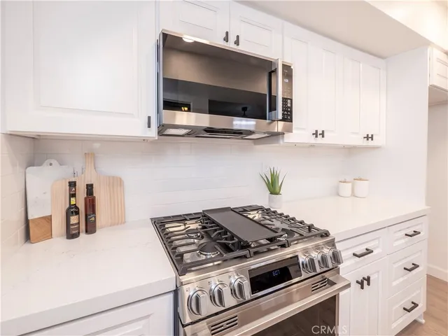 a kitchen with stainless steel appliances a stove and white cabinets