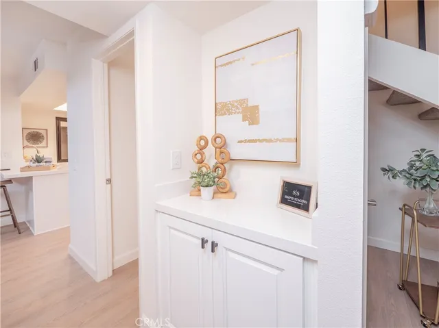 a hallway with white cabinets and wooden floor