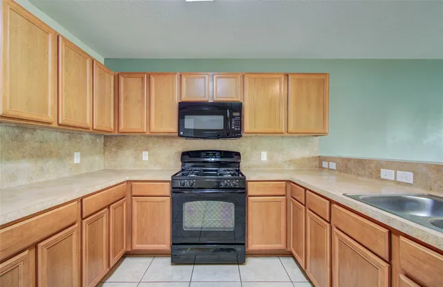a kitchen with granite countertop a sink stove and microwave