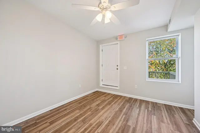 an empty room with wooden floor fan and windows