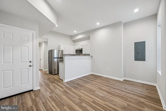 a view of a kitchen with a refrigerator wooden floor and a window