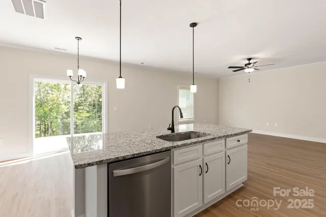a kitchen with a sink chandelier and a wooden floor