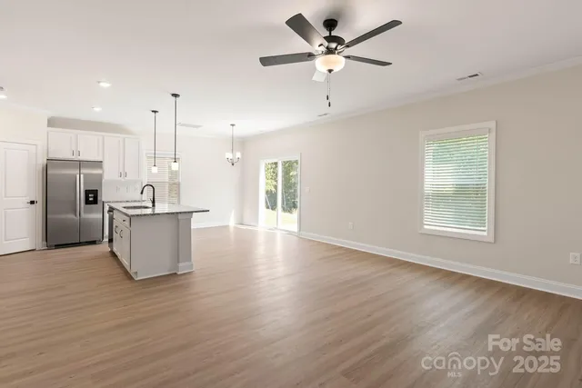 a view of an empty room with kitchen appliances and a ceiling fan