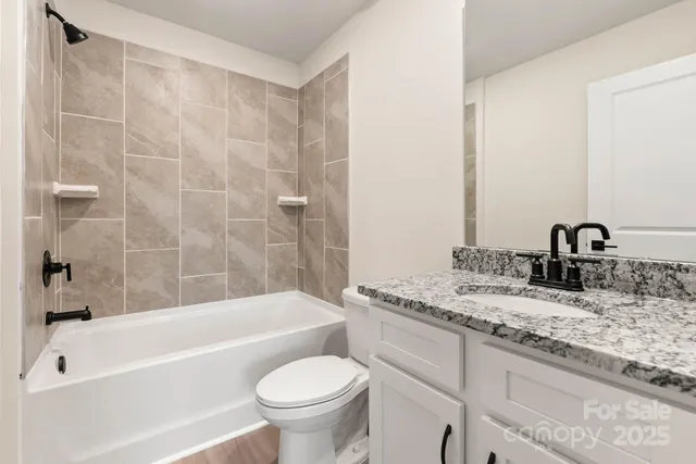 a bathroom with a granite countertop sink toilet and bathtub