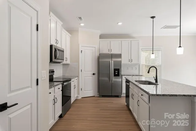 a kitchen with stainless steel appliances granite countertop a sink refrigerator and cabinets
