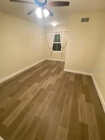 en empty room with wooden floor and ceiling fan