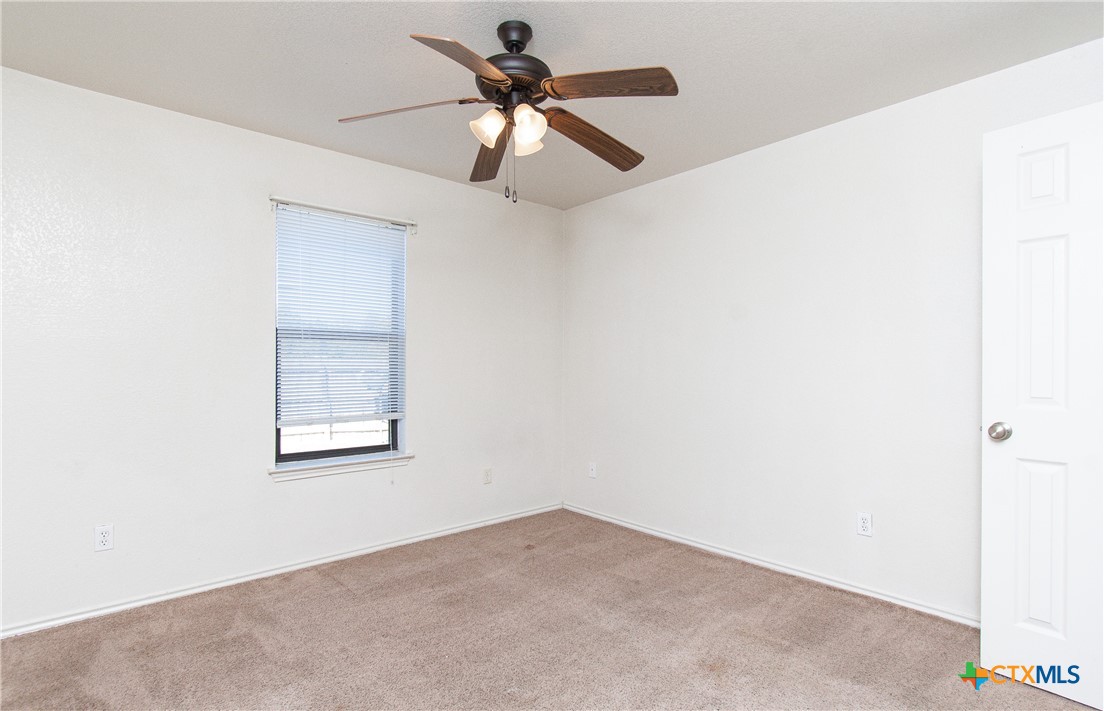 405 Bermuda Street, Unit B Copperas Cove, TX 76522 - Photo 6 of 13 an empty room with a chandelier fan and windows