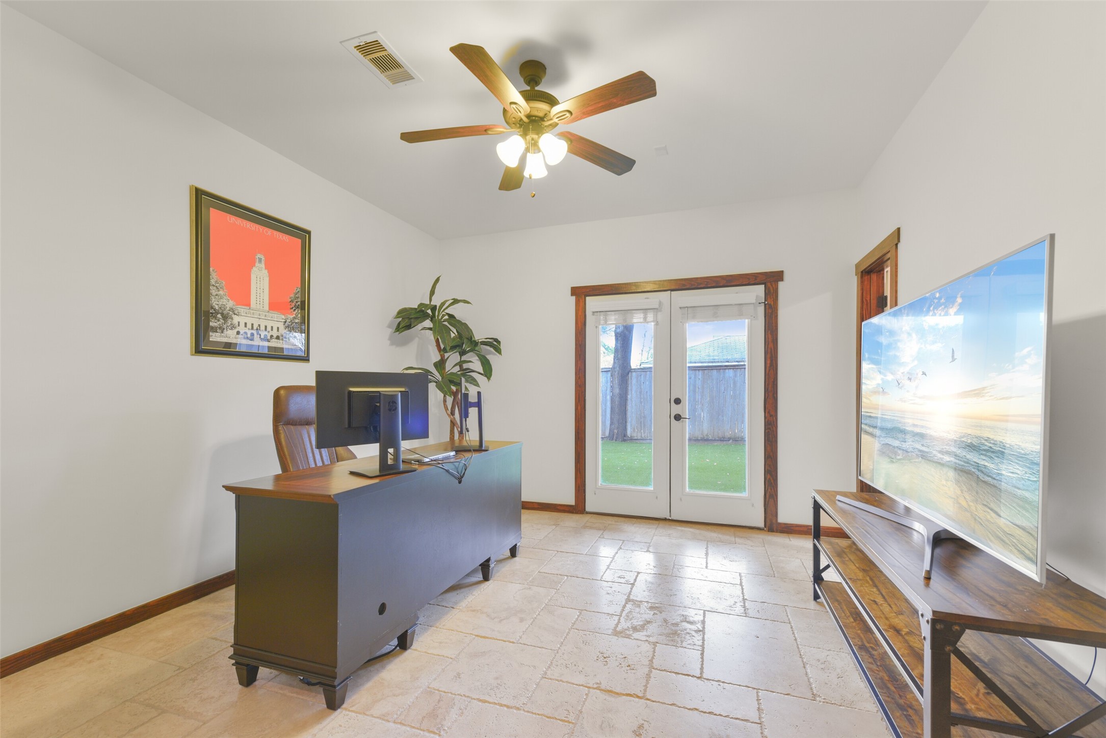 2601 Bevis Street, Unit B Houston, TX 77008 - Photo 20 of 25 Located downstairs, this versatile secondary bedroom with en-suite bathroom is perfect for a study, game room, or workout space. Featuring a beautiful travertine floor, French door entrance with window covering, and French doors with blinds that open to the backyard. A walk-in closet and ceiling fan complete this flexible space.