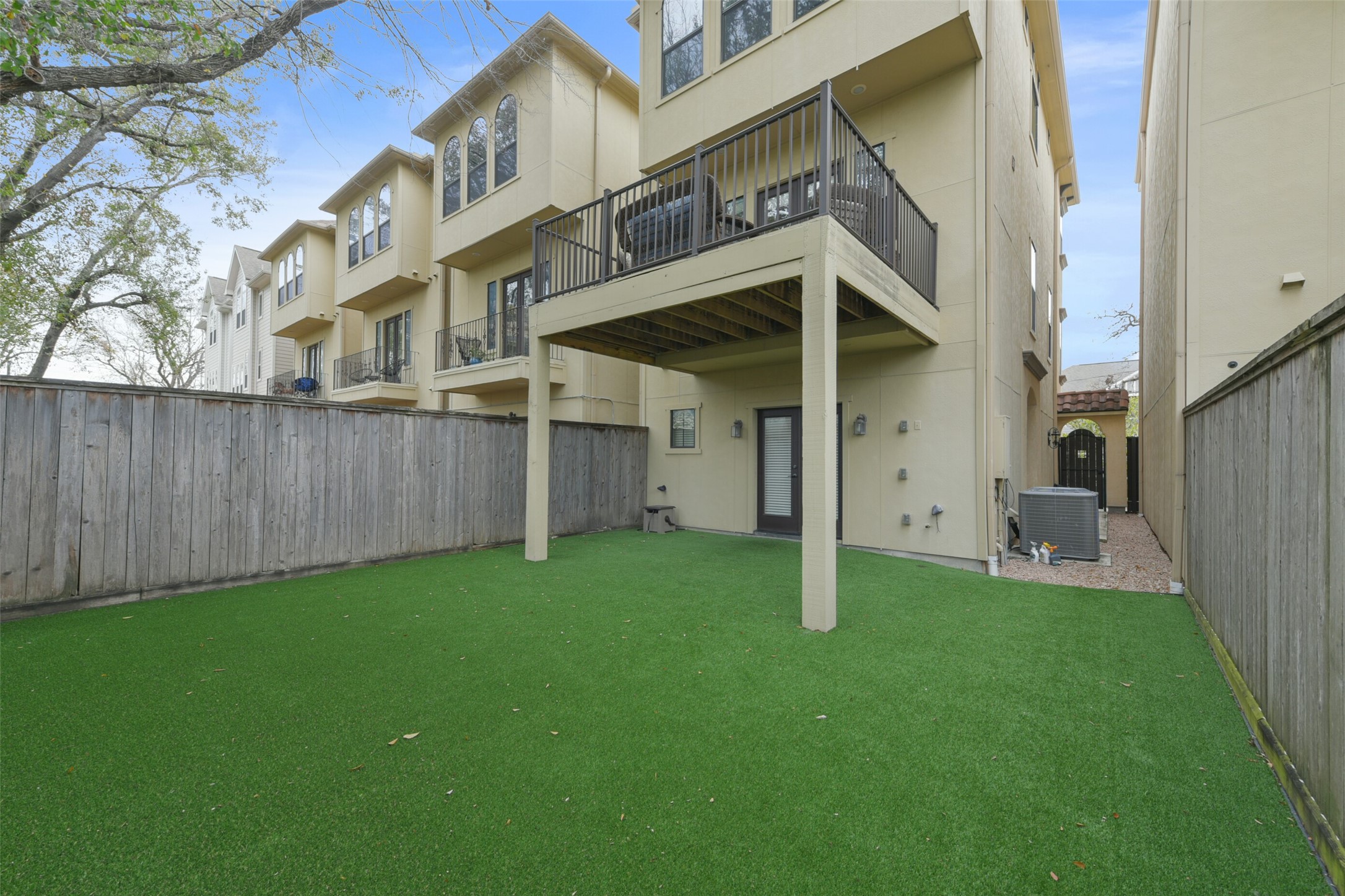 2601 Bevis Street, Unit B Houston, TX 77008 - Photo 22 of 25 Enjoy a 30' fenced backyard, perfect for pets & kids to play, with turf installed in 2021 for low-maintenance greenery. The large covered space is ideal for outdoor furniture and entertaining, complete w/ a gas line connection for your grill. Exterior lanterns add charm, while mature trees provide ample shade. Additionally, the extended second-floor patio, added in 2021, offers easy access from the kitchen, perfect for grilling & outdoor dining.
