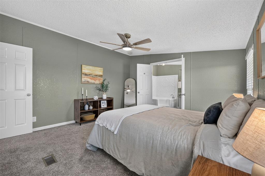 449 Big Salty Lane Springtown, TX 76082 - Photo 16 of 25 Carpeted bedroom featuring a ceiling fan with integrated lighting, a doorway to a bathroom with a white vanity, and light green painted walls