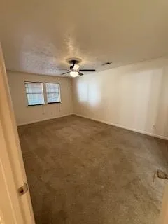 an empty room with a ceiling fan and window