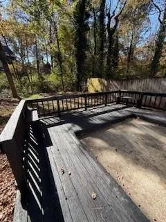 a view of a balcony with wooden floor and fence and trees