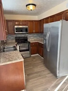a kitchen with stainless steel appliances granite countertop a refrigerator stove and sink