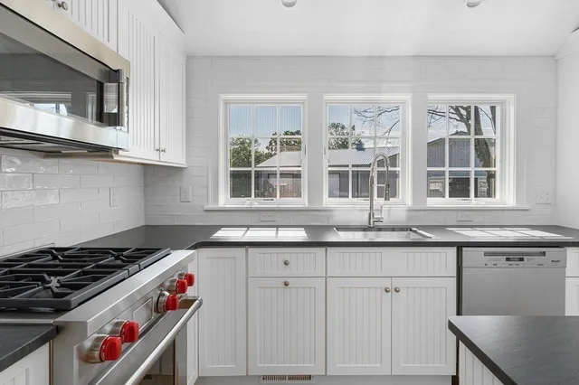 a kitchen with stainless steel appliances granite countertop a sink a stove a refrigerator cabinets and wooden floor