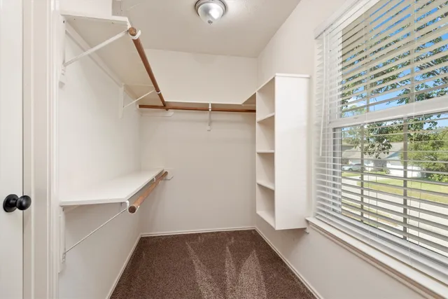 an empty room with a chandelier fan and windows