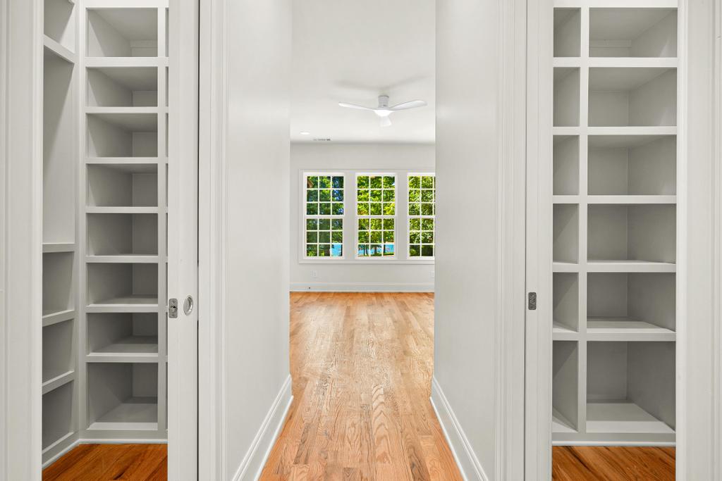 707 Vickery Street Extension Hartwell, GA 30643 - Photo 24 of 50 Built-in shelving flanks a sunlit passage leading to a room with serene outdoor views.