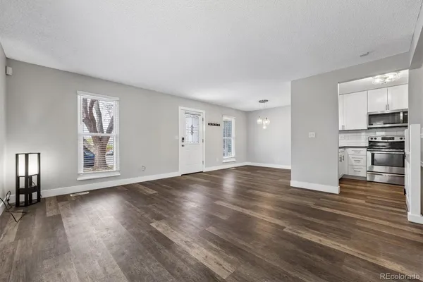 a view of empty room with wooden floor and kitchen