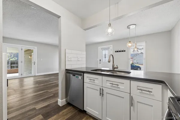 a kitchen with granite countertop white cabinets and a wooden floor