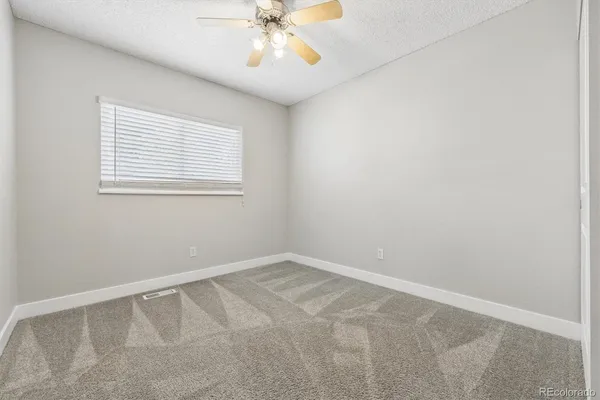 an empty room with a window and chandelier fan