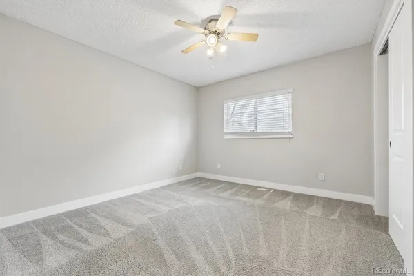 an empty room with windows and fan