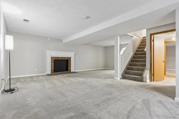 a view of an empty room with stairs and a fireplace