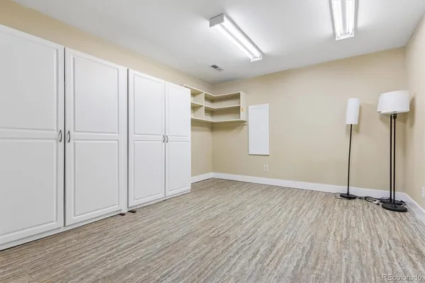 an empty room with wooden floor closet and windows