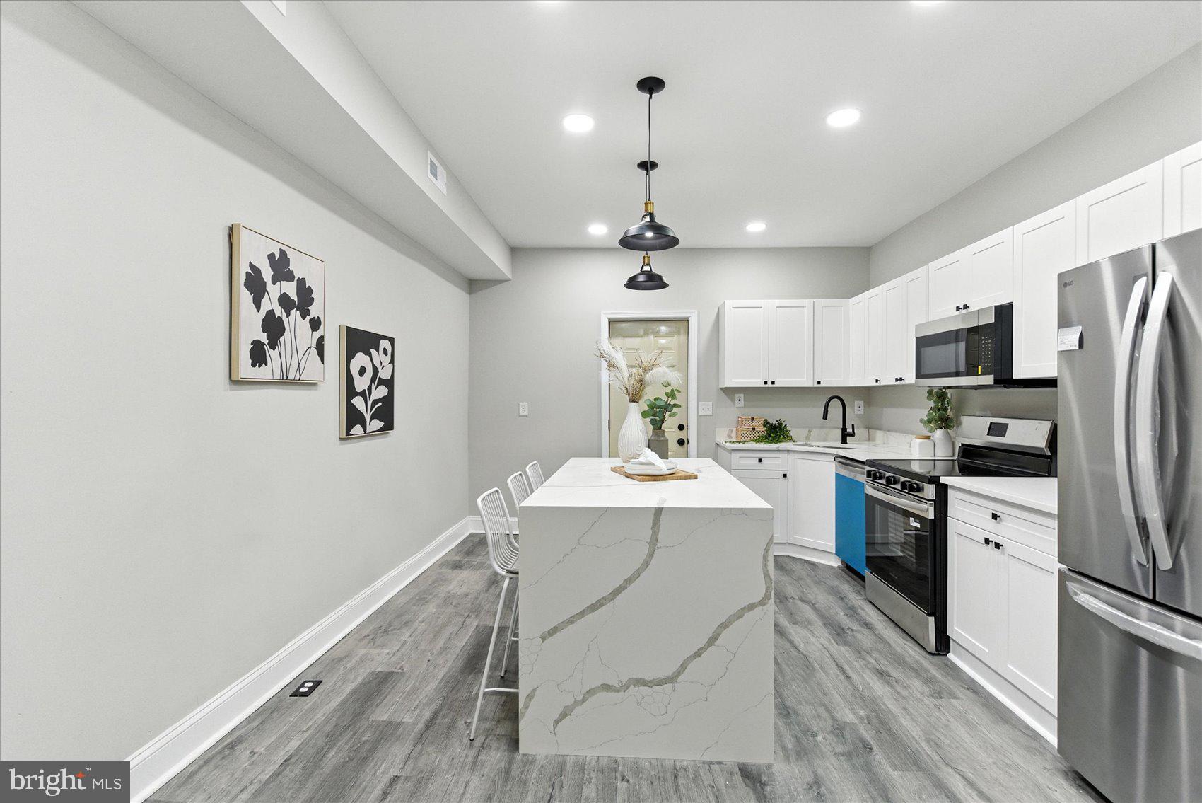 1607 Montpelier Street Baltimore, MD 21218 - Photo 8 of 37 a kitchen with a refrigerator a sink dishwasher a stove and white cabinets with wooden floor